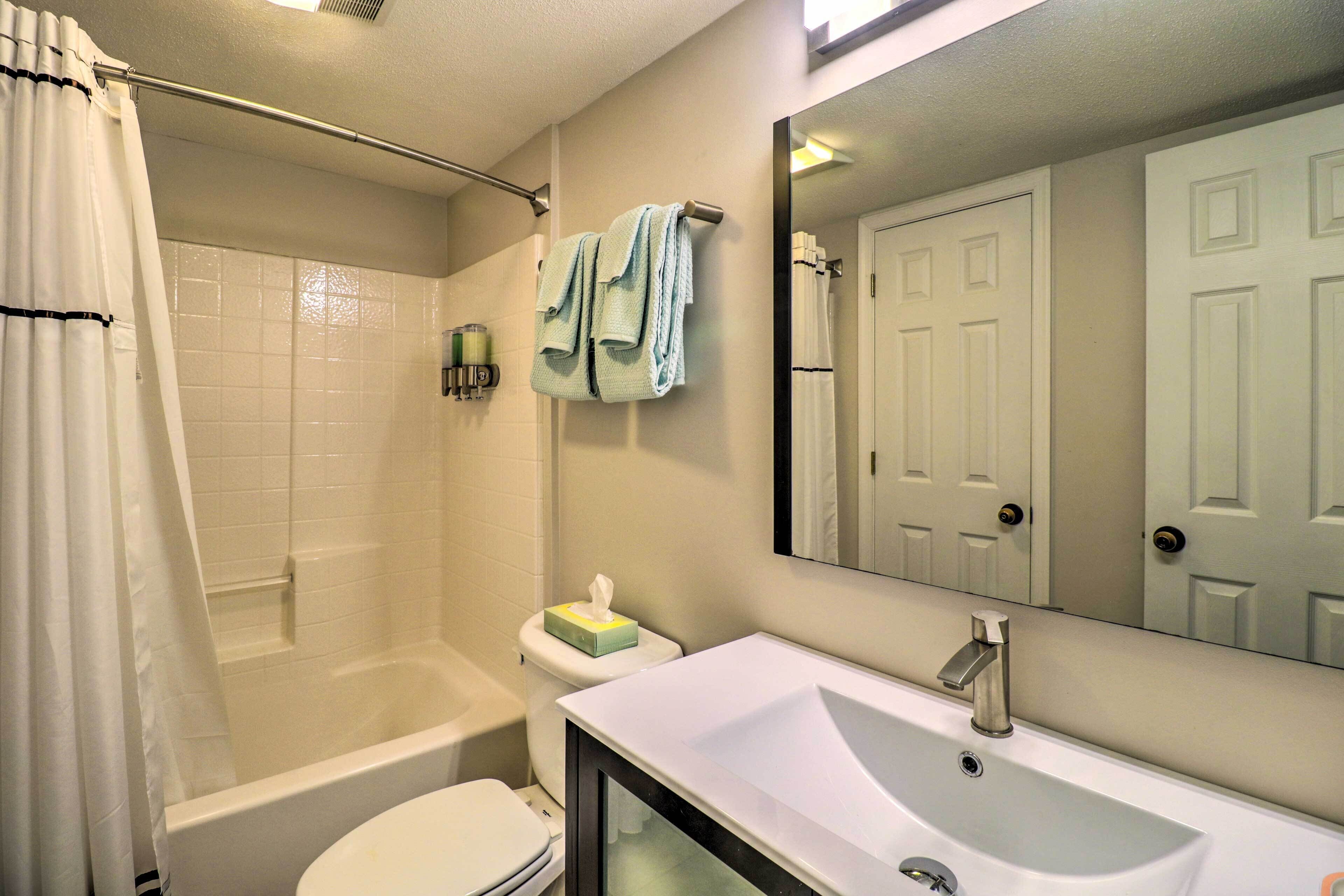 A bathroom with a bathtub, toilet, sink, and a mirror.