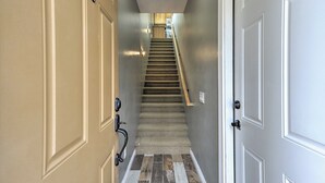 Un corridoio con una scala tappezzata che conduce a una zona cucina.
