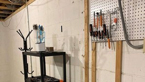 A utility room with a pegboard wall, a metal shelving unit, and storage bins.