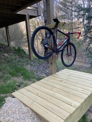 Une terrasse en bois avec un vélo appuyé contre un poteau.