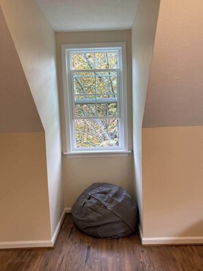 A corner room with a window, a wooden floor, and a bean bag chair. - VeloWay Chalet by Buffalo Mountain Getaway (Willis)
