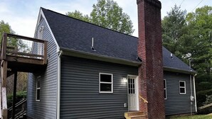 A two-story house with a brick chimney, a front porch, and a small front yard.