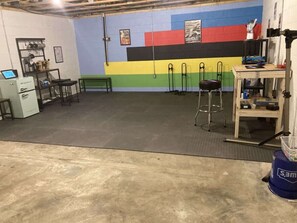 A gym with a colorful wall, exercise equipment, and a desk with a computer. - VeloWay Chalet by Buffalo Mountain Getaway (Willis)
