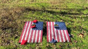 A rustic barn in a field with two picnic blankets featuring the American flag design.
