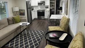 A compact living space with a kitchenette, a dining area, and a seating area with a sofa and chairs.
