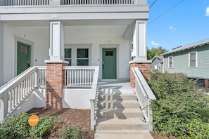 Stunning two-story residence with a charming entrance, complete with a green door and brick column.