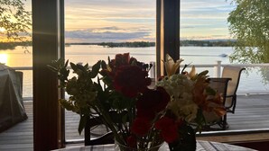Una mesa con un jarrón de flores y vista a un lago al atardecer.