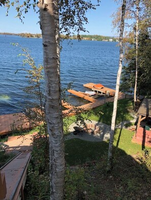 Enjoy serene lakeside views from a peaceful outdoor space surrounded by lush greenery and a wooden dock.