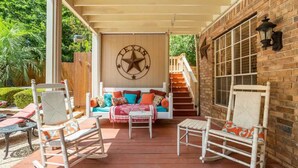 Een overdekte patio met schommelstoelen, een bank met kleurrijke kussens en een decoratie van een ster van Texas.