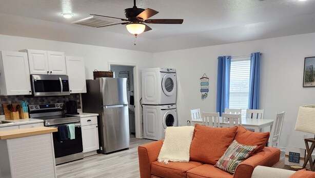 Un espacio habitable compacto con kitchenette, sofá, zona de comedor y ventilador de techo.