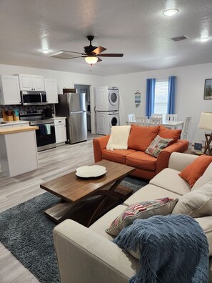 A compact living space with a kitchenette, a sofa set, a dining area, and a ceiling fan.