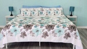 Un dormitorio con colcha estampada de flores, decoración de estrellas en la pared y alfombra con diseño.