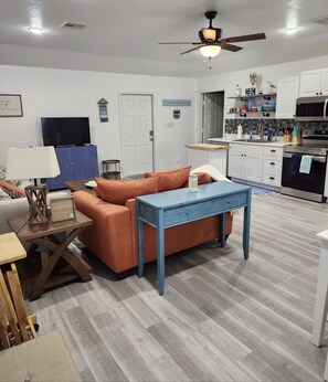Relax in this stylish living space with a comfortable sofa, TV, and modern kitchen.
