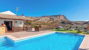 Una piscina con vista a la montaña, cerca de una valla de madera y un edificio con una puerta.
