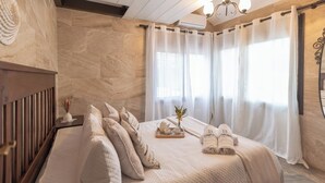 Ein Spa-Raum mit Bett, Handtüchern, einer Ablage mit Teetassen und einer Vase mit Blumen.