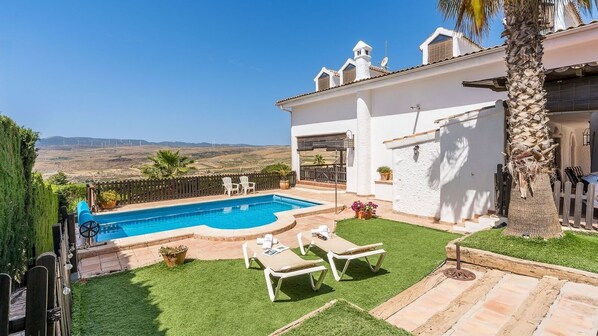 A backyard with a swimming pool, two lounge chairs, a small table, and a view of the countryside. - El Collado de Lecrín El Padul by Ruralidays (Granada)