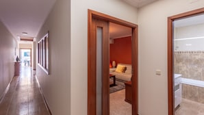 A hallway with a wooden door leading to a living area with a sofa and a coffee table. - Porto Residence Campanhã (Oporto)