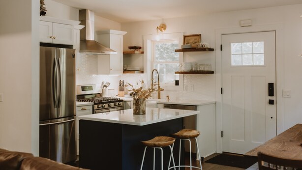 A modern kitchen with white cabinetry, stainless steel appliances, and a central island with stools. - Antique Charm 8 Mins to Stratton 12 to Mt Snow (Stratton)