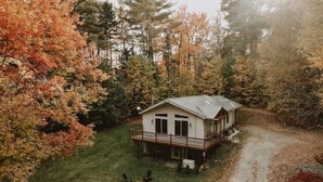A cabin with a deck and outdoor seating, surrounded by autumn foliage. - Antique Charm 8 Mins to Stratton 12 to Mt Snow (Stratton)