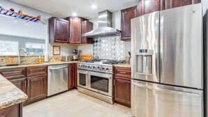 A modern kitchen with stainless steel appliances, wooden cabinets, and a granite countertop.