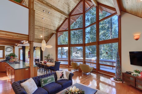 A spacious living area with a large wooden ceiling, a dining area with a kitchen, and a balcony with a view of trees.. 🌄 Luxe A-Frame Panoramic View Yosemite West Cabin - NEW AC and EV Charger🌄