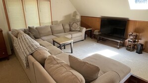 Amplia sala de estar con un sofá grande, un televisor y techo de madera.