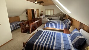 Un dormitorio con dos camas, ventilador de techo y techo inclinado con tragaluz.