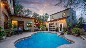 A backyard with a swimming pool, outdoor furniture, and string lights.