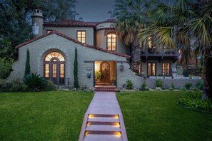 A Mediterranean-style house with a stone facade, arched windows, and a well-lit entrance.