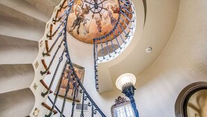 A spiral staircase with ornate metal railings and a decorative ceiling.