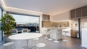 Une cuisine moderne dotée d’un grand îlot central, de tabourets de bar et d’un coin repas avec une table ronde.
