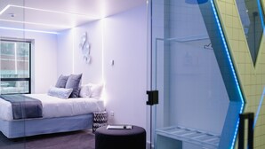 Une chambre à coucher moderne avec un lit, une table de chevet et une cabine de douche en verre.