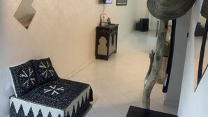Un salon comprenant un canapé, un téléviseur, une petite table et un miroir décoratif.