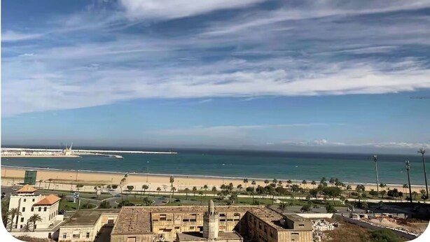 Une vue sur la côte, avec une plage, des bâtiments et un ciel dégagé.