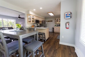 A modern kitchen with wooden cabinets, a central island, and a dining area with a table and chairs.