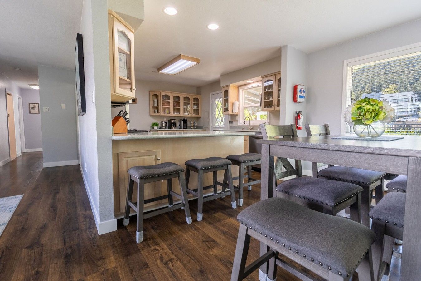 A modern kitchen with wooden cabinets, a bar area, and a dining table with bar stools.