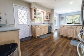 A modern kitchen with wooden cabinets, a dishwasher, and a window providing natural light.