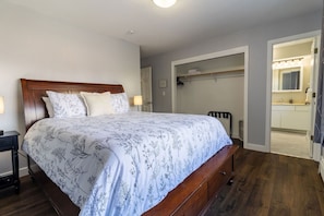 A bedroom with a large bed, a bedside table, a wardrobe, and a bathroom visible through an open door. - MountainView Getaway - Spacious Home, Sleeps 11 (Seward)