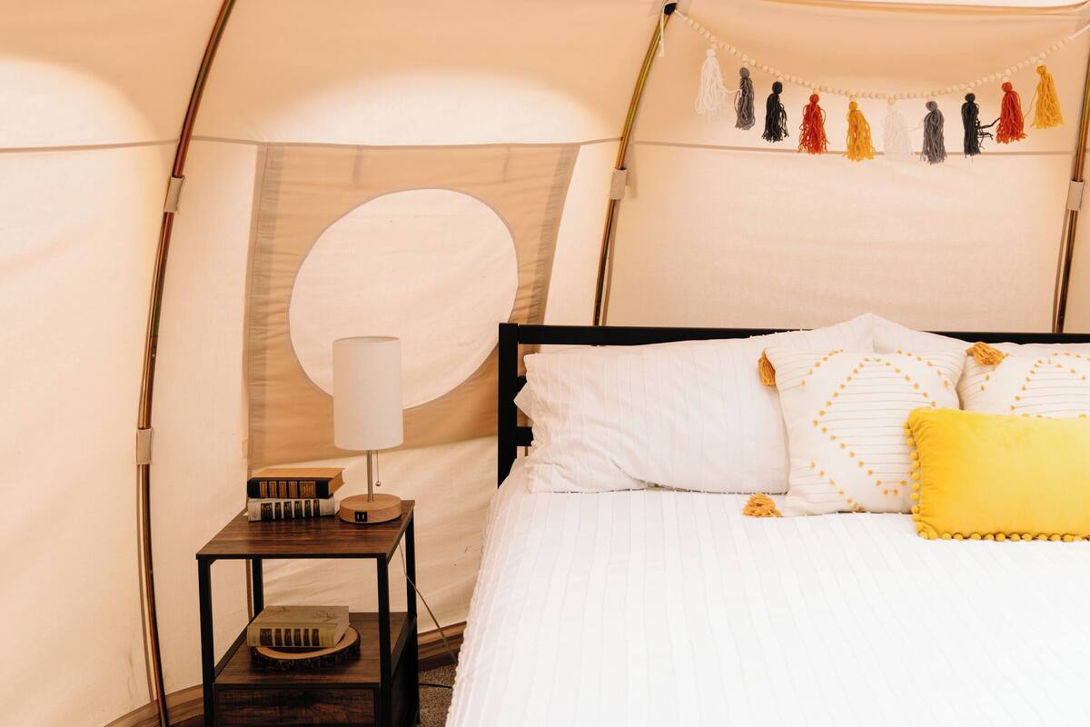 A tented room with a bed, a nightstand, and a lamp.