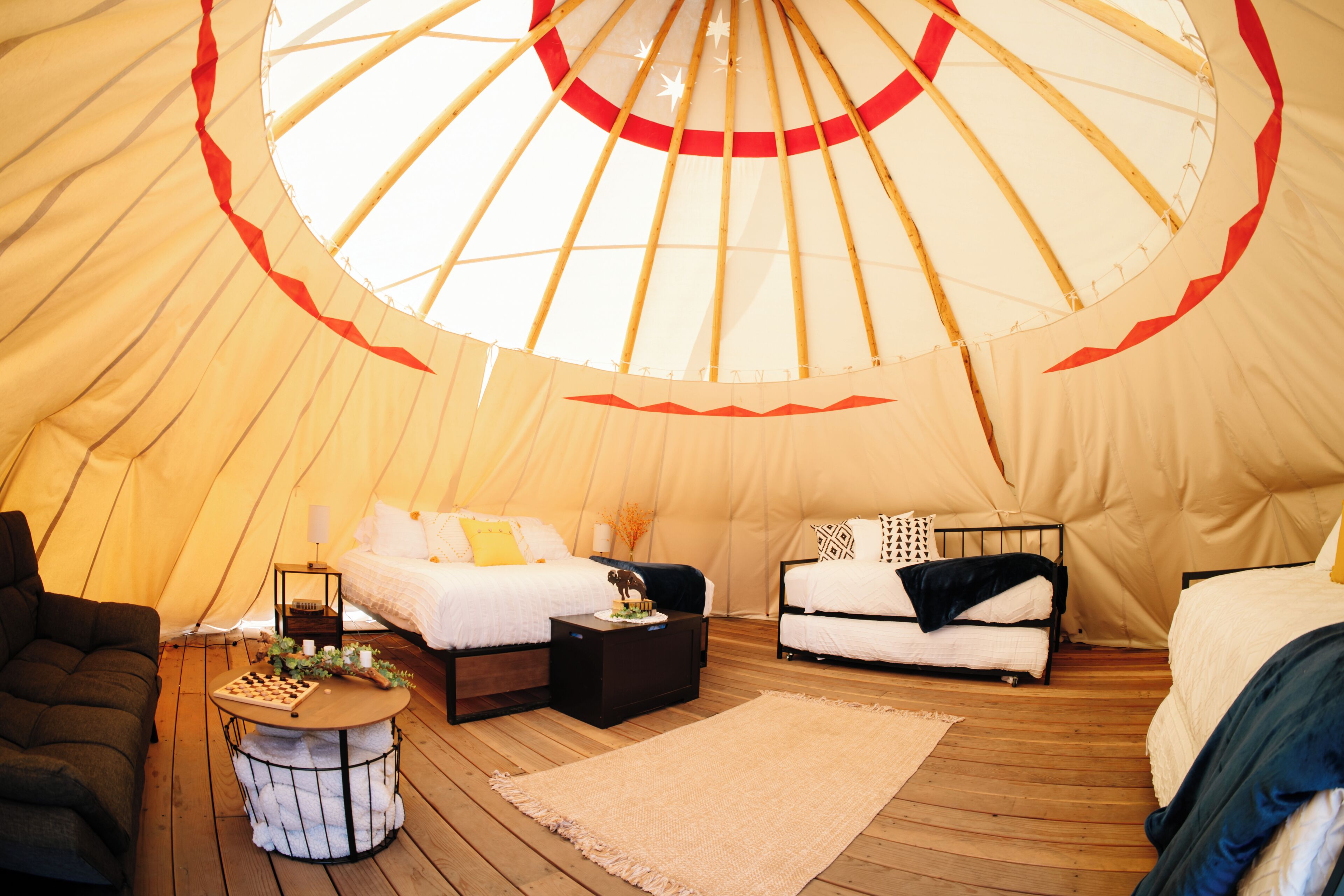 Een tent met twee bedden, een tafeltje en een bank.