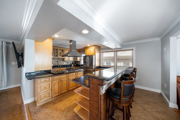 A spacious kitchen with a central island, wooden cabinets, and a large refrigerator. - Home in Linden (Linden)
