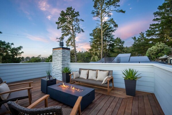 A rooftop deck with a fire pit, seating area, and a chimney. - Luxe Surf Shack | Rooftop Hot Tub, Games + Near Beach (Bodega Bay)