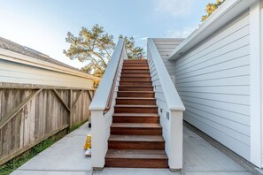 A wooden staircase with a white handrail leading to a house with white siding. - Luxe Surf Shack | Rooftop Hot Tub, Games + Near Beach (Bodega Bay)