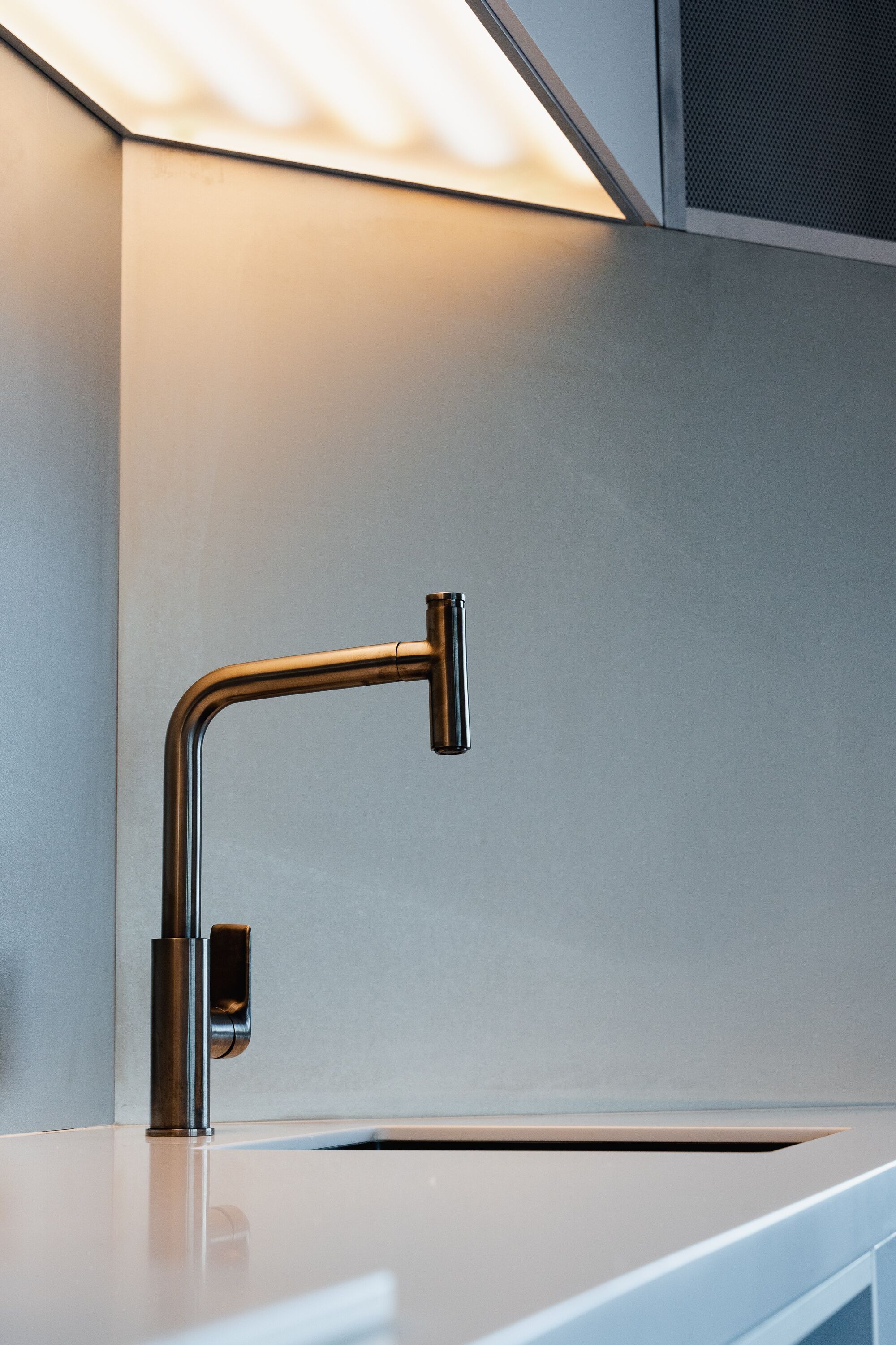 A modern kitchen with a stainless steel faucet and a white countertop.