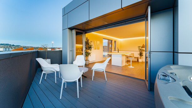 En moderne udendørs terrasse med hvide stole og en grill.