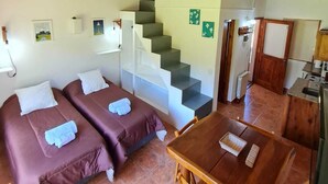 A cozy room with two beds, a wooden table, and a staircase. - CERRO CATEDRAL SCHUSS ARG41 (San Carlos de Bariloche)