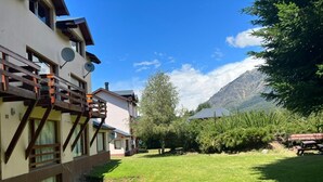 A building with a balcony, a grassy yard, and a mountain in the background. - CERRO CATEDRAL SCHUSS ARG41 (San Carlos de Bariloche)