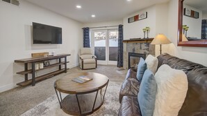 A living room with a sofa, a coffee table, a TV, a fireplace, and a sliding glass door. - Empire Coalition Ski Condo - Walking distance to PC Mtn - Free bus route (Park City)