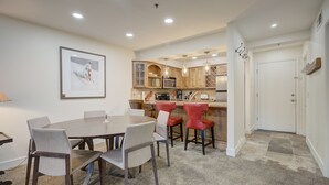 A modern kitchen with wooden cabinets, a dining area with a round table and chairs, and a hallway leading to a door. - Empire Coalition Ski Condo - Walking distance to PC Mtn - Free bus route (Park City)