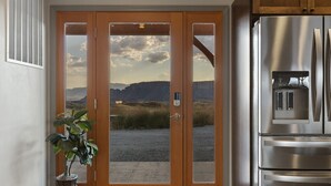Eine Küche mit einem Edelstahl-Kühlschrank und einer Holztür, die einen Blick auf die Berge freigibt.
